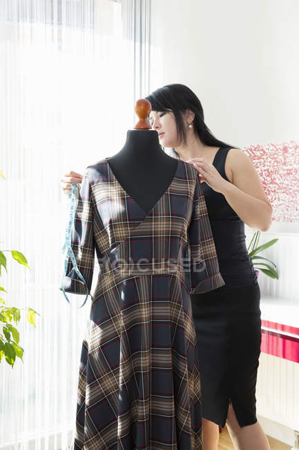 Зрелая женщина портниха измеряет платье в гостиной — стоковое фото