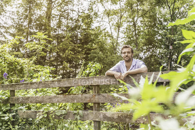Retrato de homem adulto médio inclinado sobre cerca de jardim — Fotografia de Stock