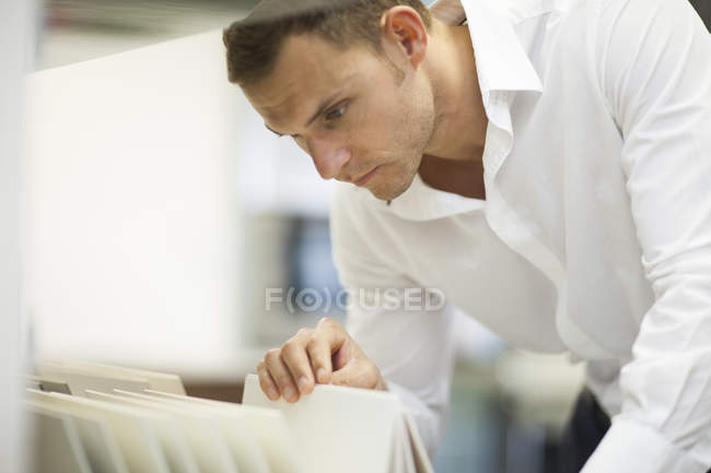 Salesman searching in filing cabinet in kitchen showroom — Stock Photo