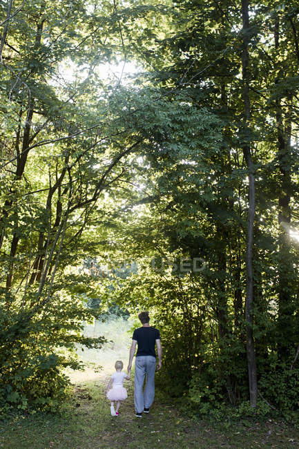 Батько і дочка йдуть лісом, вид ззаду — стокове фото