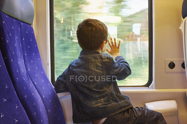 Visão traseira do menino com a mão contra a janela de trem — Fotografia de Stock