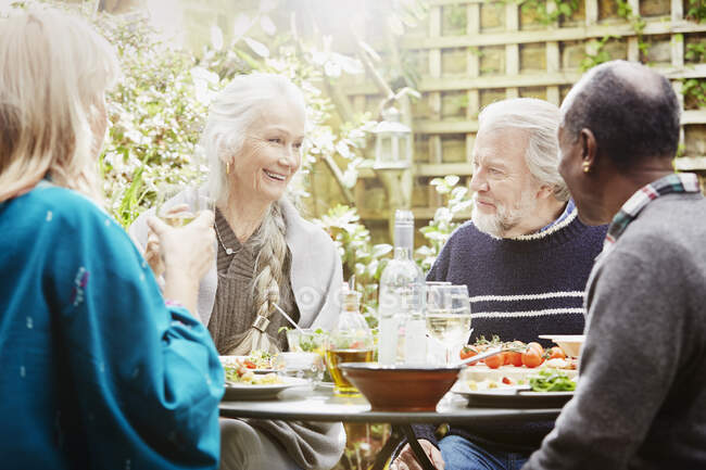 Старшие друзья едят еду в саду — стоковое фото