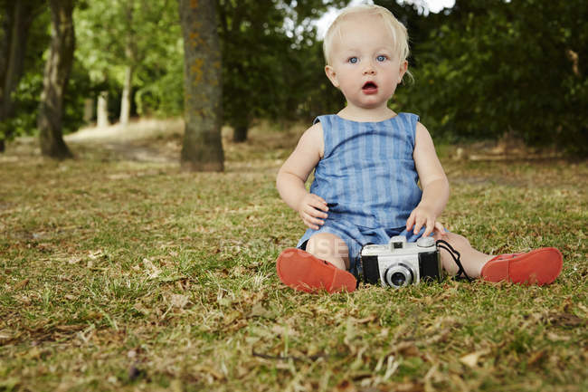 Девочка сидит на траве с кинокамерой — стоковое фото