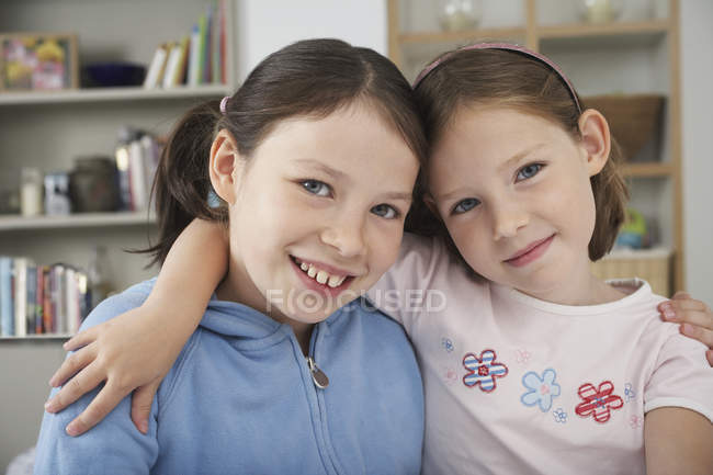 Retrato de hermanas de edad elemental en la cocina casera - foto de stock