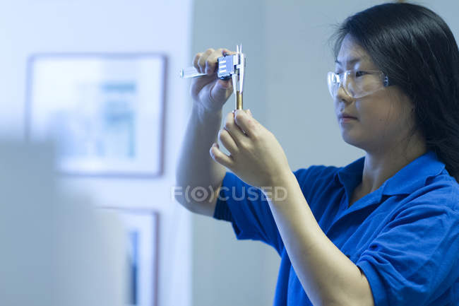 Mujer joven que utiliza un dispositivo de medición especializado - foto de stock