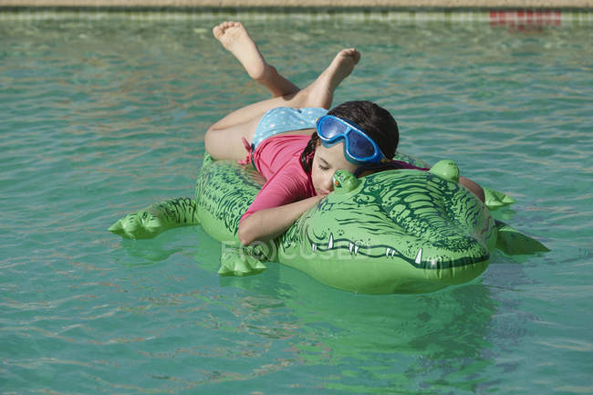 Young girl relaxing on inflatable in swimming pool — Stock Photo