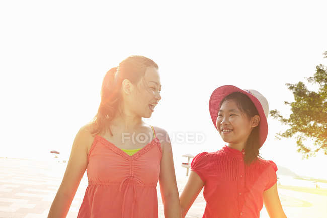 Donna e figlia passeggiano sulla spiaggia illuminata dal sole — Foto stock
