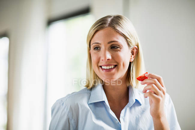 Молода жінка їсть скибочки помідорів — стокове фото