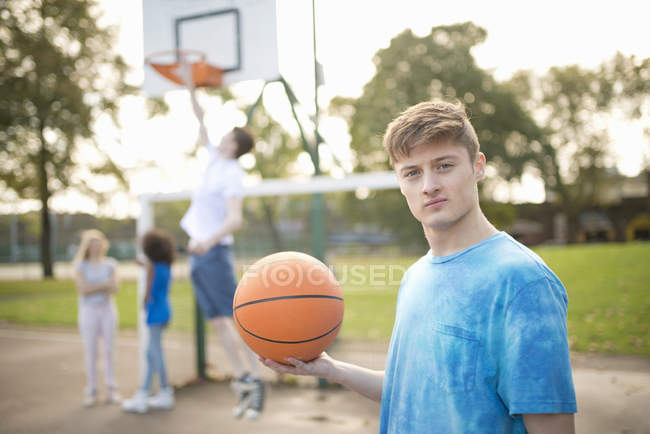 Porträt eines jungen männlichen Basketballspielers mit Basketballkorb — Stockfoto