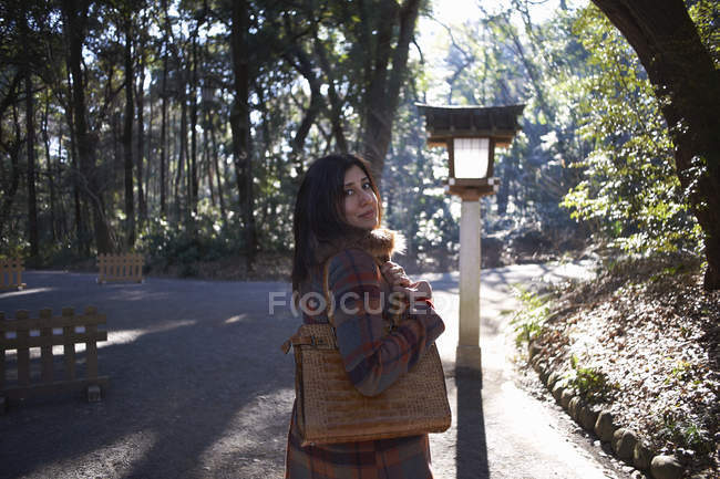 Portrait of mature female tourist looking over her shoulder in park, Tokyo, Japan — Stock Photo