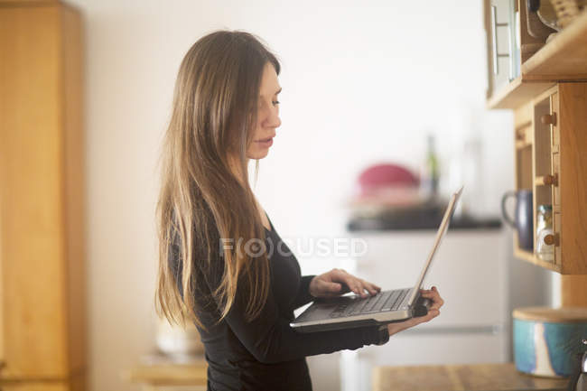 Молода жінка вдома, використовуючи ноутбук — стокове фото