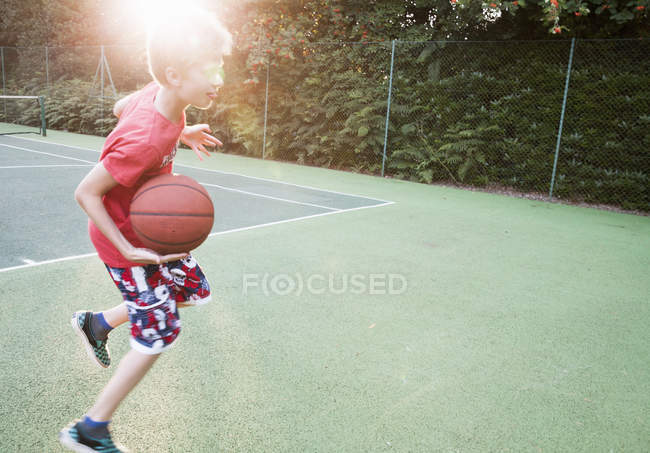 Niño jugando baloncesto en retroiluminación en el parque - foto de stock