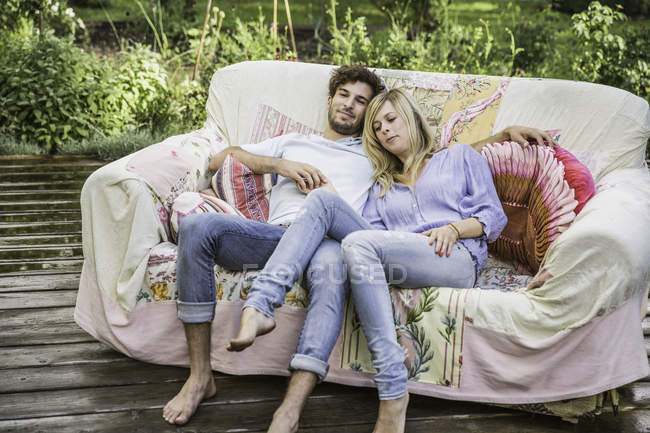 Пара розслабляється на старовинному дивані в саду — стокове фото