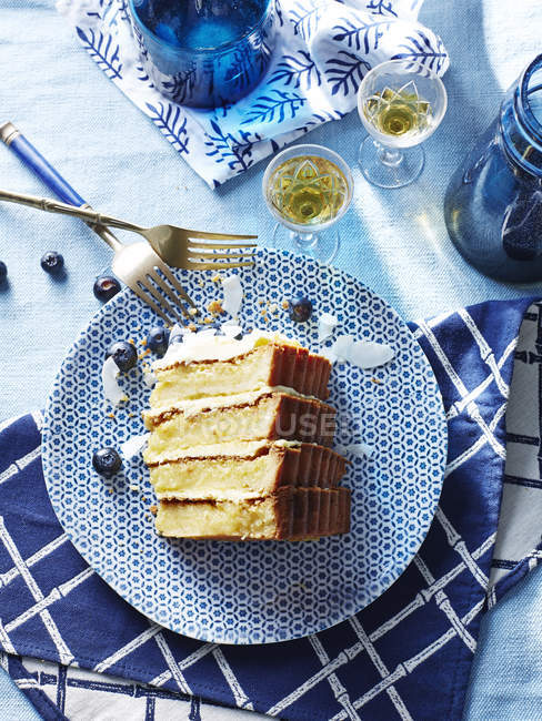 Scheibe von vier Stapelkuchen mit Blaubeeren auf blauem Teller — Stockfoto