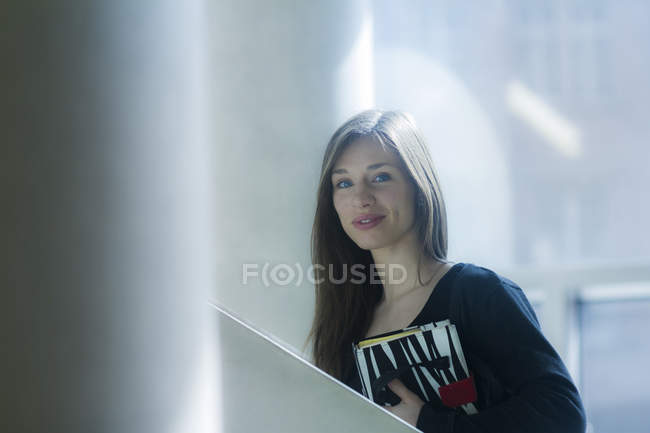 Woman carrying notebook looking at camera smiling — Stock Photo