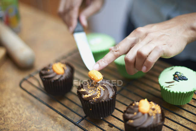 Mãos femininas gelando bolos de copos no rack de refrigeração — Fotografia de Stock