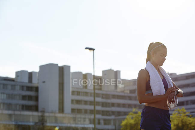 Молода жінка бігунка перевіряє розумний годинник на міському даху — стокове фото