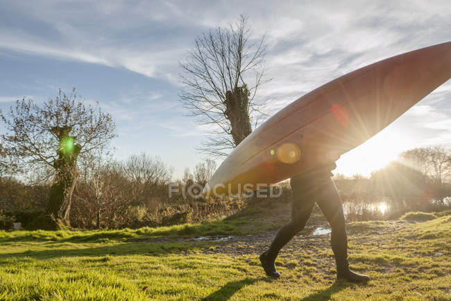 Vista laterale della donna che trasporta canoa in campo — Foto stock