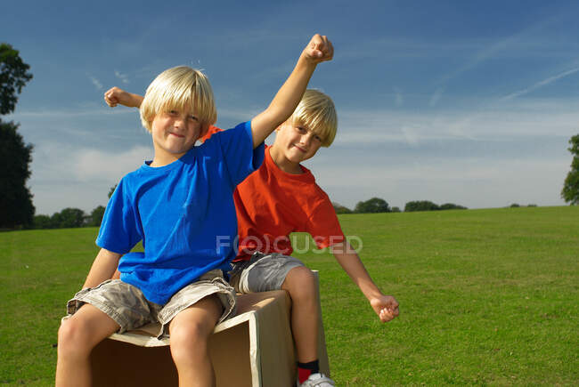 Boys on a box, arms out — Stock Photo