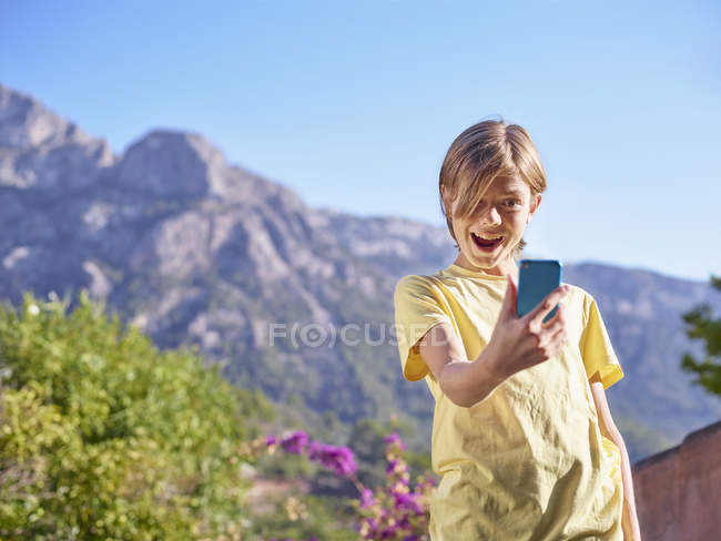 Мальчик делает лицо для селфи на смартфоне, Майорка, Испания — стоковое фото