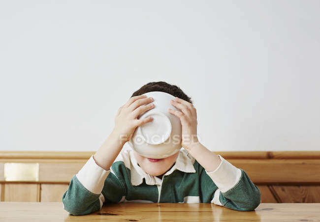 Мальчик пьет молоко из миски — стоковое фото