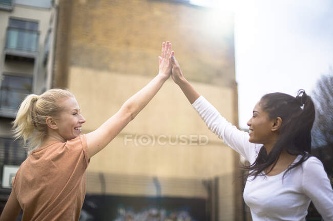 Две молодые женщины дают пять, на открытом воздухе — стоковое фото