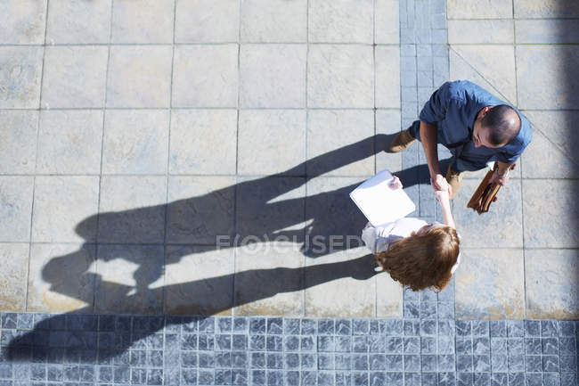 Businessman and business woman shaking hands, overhead view — Stock Photo