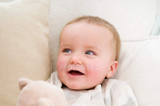 Un bebé sonriendo sosteniendo un oso - foto de stock