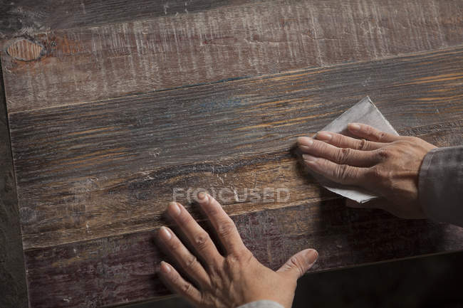 Carpenter smoothing surface of wood plank with sandpaper in factory, Jiangsu, China — Stock Photo