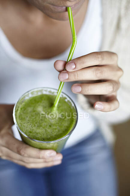 Donna che beve frullato verde con paglia — Foto stock