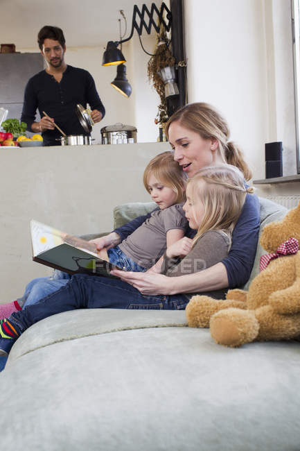Mother and two daughters reading storybook — Stock Photo
