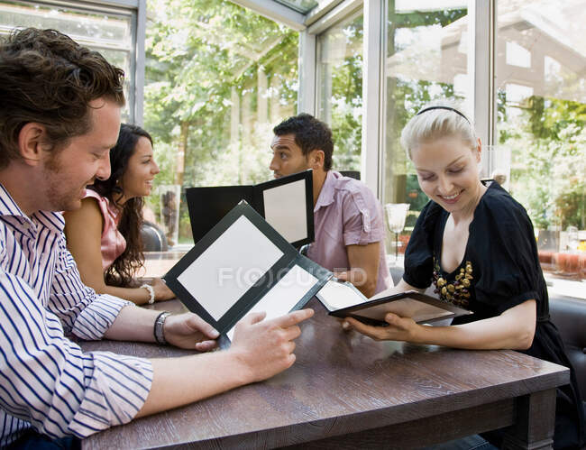 Men and women talking over menus — Stock Photo