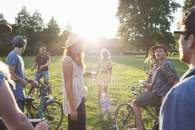 Group of party going adults arriving in park on bicycles at sunset — Stock Photo