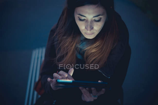 Mulher adulta média usando tablet digital touchscreen na plataforma ferroviária ao entardecer — Fotografia de Stock