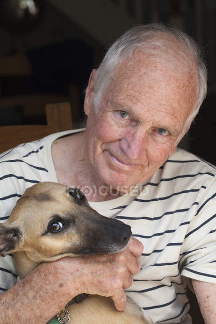 Старший мужчина держит собаку — стоковое фото