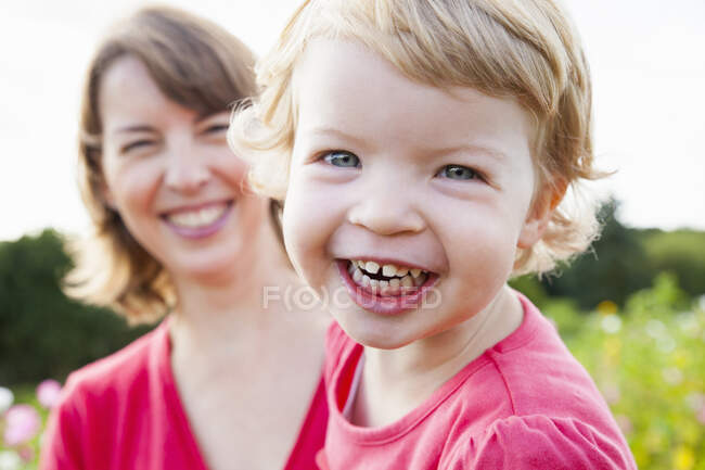 Close up retrato de mãe adulta média e filha criança no campo de flores — Fotografia de Stock