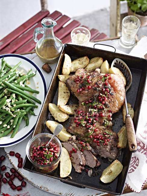 Roast lamb with pomegranate seeds and vegetables — Stock Photo