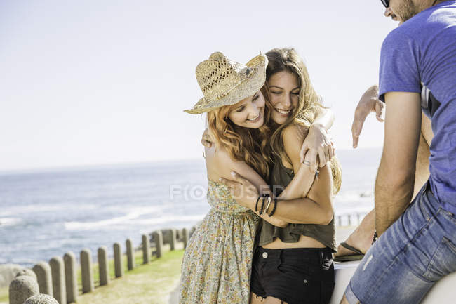 Amigos adultos que se abrazan en la costa, Ciudad del Cabo, Sudáfrica - foto de stock