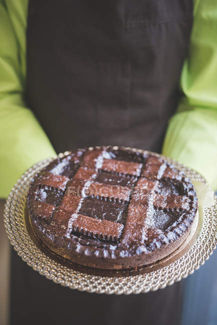 Cameriere che trasporta piatto di torta al cioccolato, colpo ritagliato — Foto stock