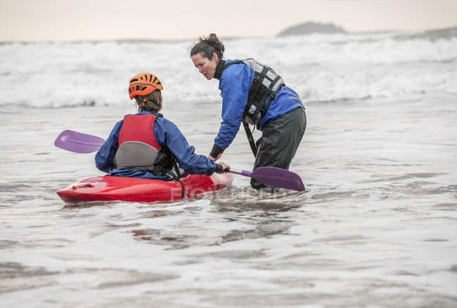 Female instructor helping woman in sea kayak — Stock Photo