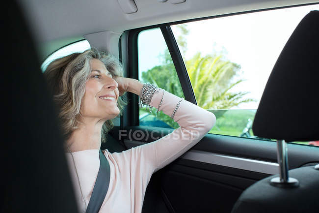 Femme d'affaires senior regardant par la fenêtre de la voiture — Photo de stock