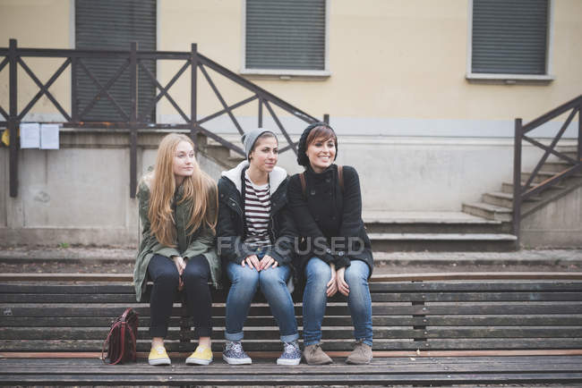 Tres hermanas sentadas en el banco del parque - foto de stock
