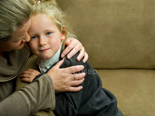 Ein junges Mädchen wird von ihrer Mutter umarmt — Stockfoto