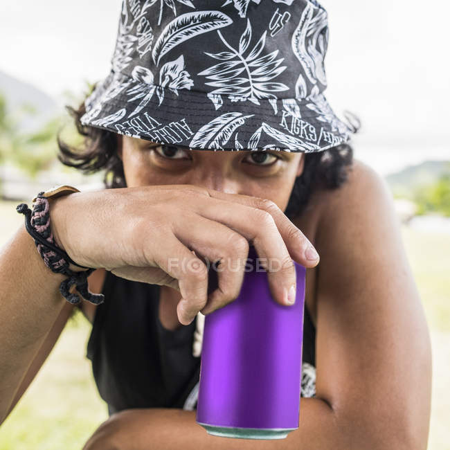 Retrato de cerca de un joven con sombrero de sol bebiendo de lata - foto de stock
