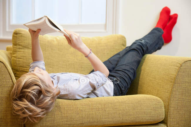 Giovane ragazzo che legge su una poltrona — Foto stock