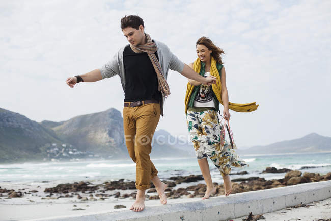 Jeune couple marchant le long d'un bloc de ciment sur la plage, Cape Town, Western Cape, Afrique du Sud — Photo de stock
