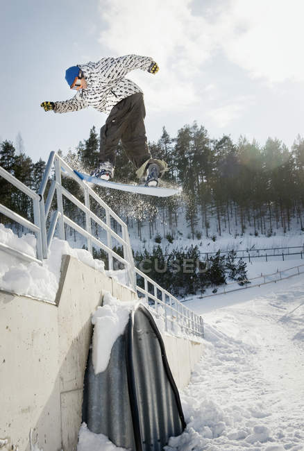 Male snowboarder jumping backwards from railings — Stock Photo