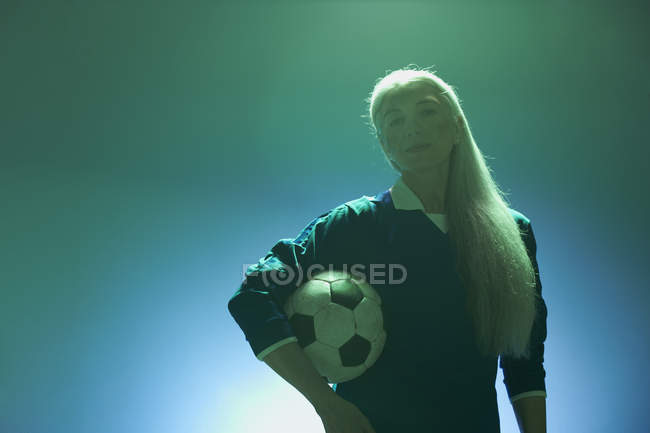 Mujer madura sosteniendo el fútbol, retroiluminado - foto de stock