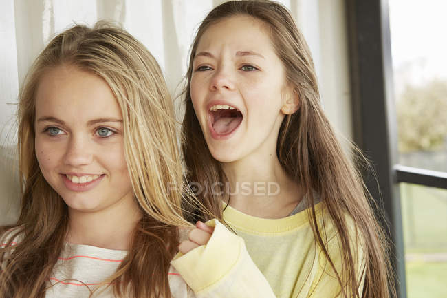 Two girls smiling and shouting from shelter — Stock Photo