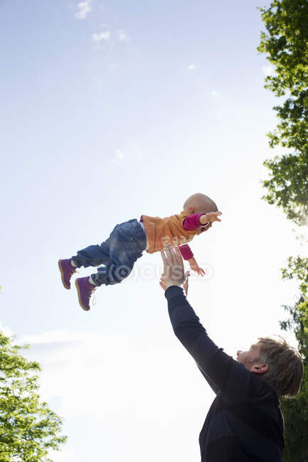 Отец бросает маленькую дочь в парке — стоковое фото